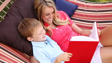 A woman and boy sitting on the couch reading.